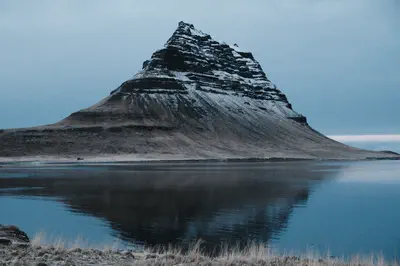 Kirkjufell mountain reflected in still water in Iceland